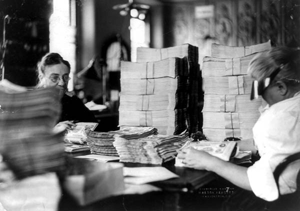 Staff inspecting and counting banknotes.